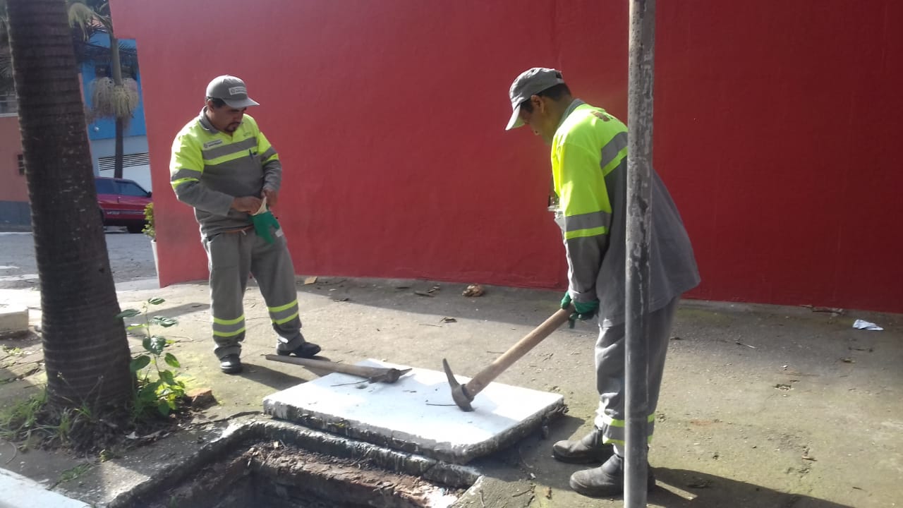 Dois trabalhadores limpando um bueiro na Rua Labatut