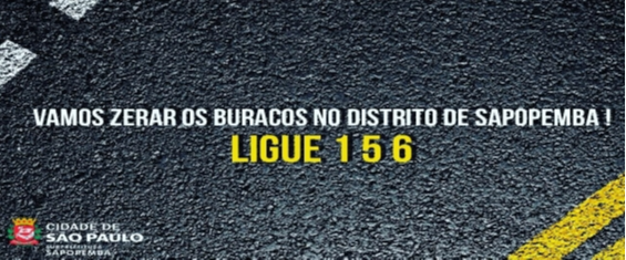 Pra Cego Ver. Imagem meramente ilustrativa como um asafalto ao fundo e a acima dele escrito em branco, "vamos Zerar os Buracos no Distrito de Sapopemba!" ao canto inferior esquerdo, o logo da Subprefeitura Sapopemba.