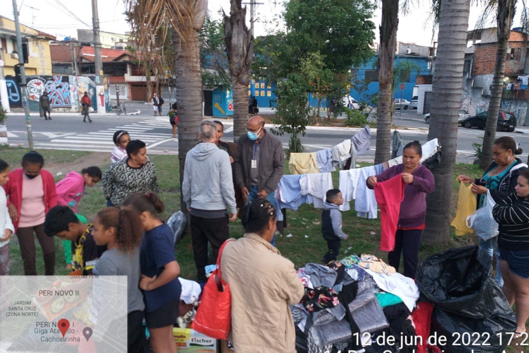 Pessoas reunidas numa praça garimpam peças doadas.