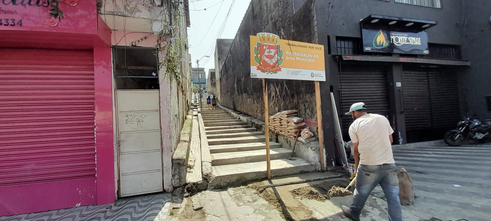 Homem prepara cimento  diante da escadaria