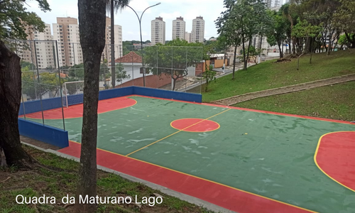 Quadra poliesportiva surge ao fundo, entre árvores da praça