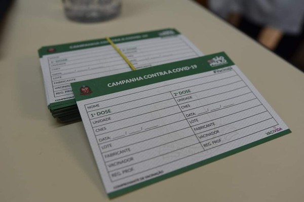 Empilhado de carteiras de vacinação contra a Covid-19 em cima de uma mesa