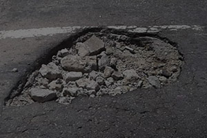 #PraCegoVer : A foto mostra um buraco na via antes da operação tapa buraco.
