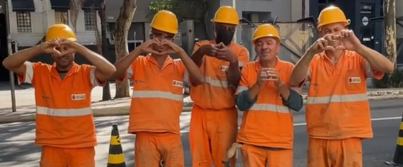 Imagem dos trabalhadores de zeladoria fazendo coração com as mãos.