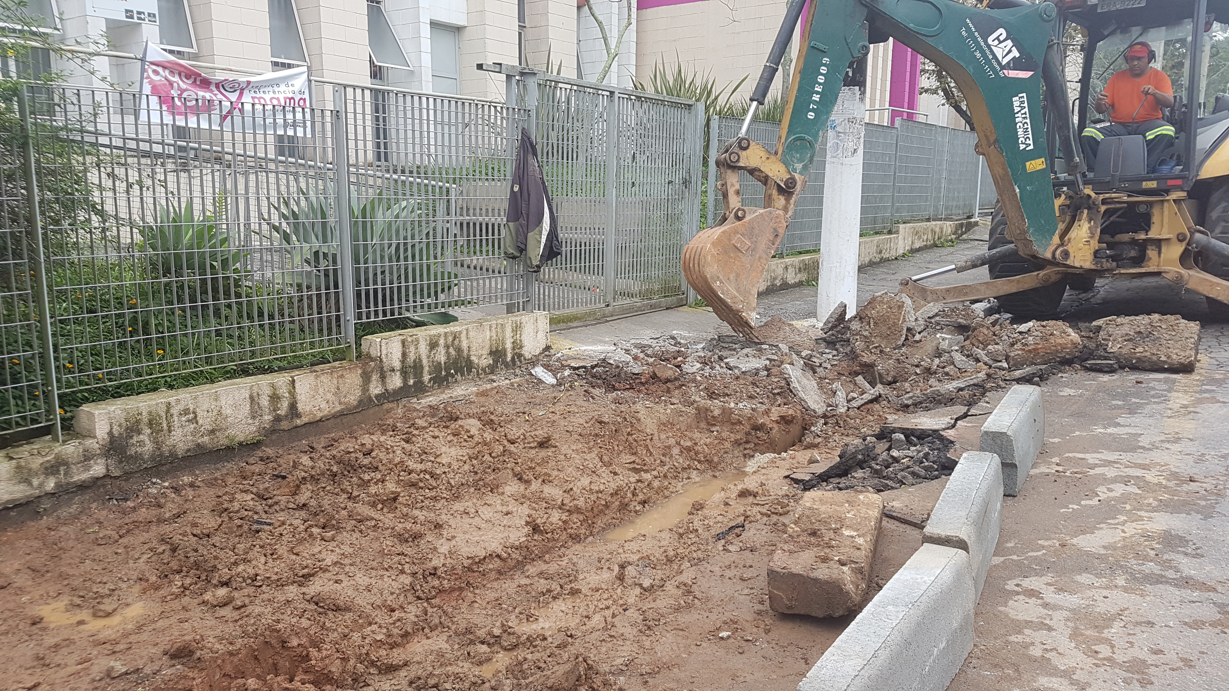 Imagem mostra um homem trabalhando em um trator reitrando o entulho de uma parte da calçada que está sendo feita