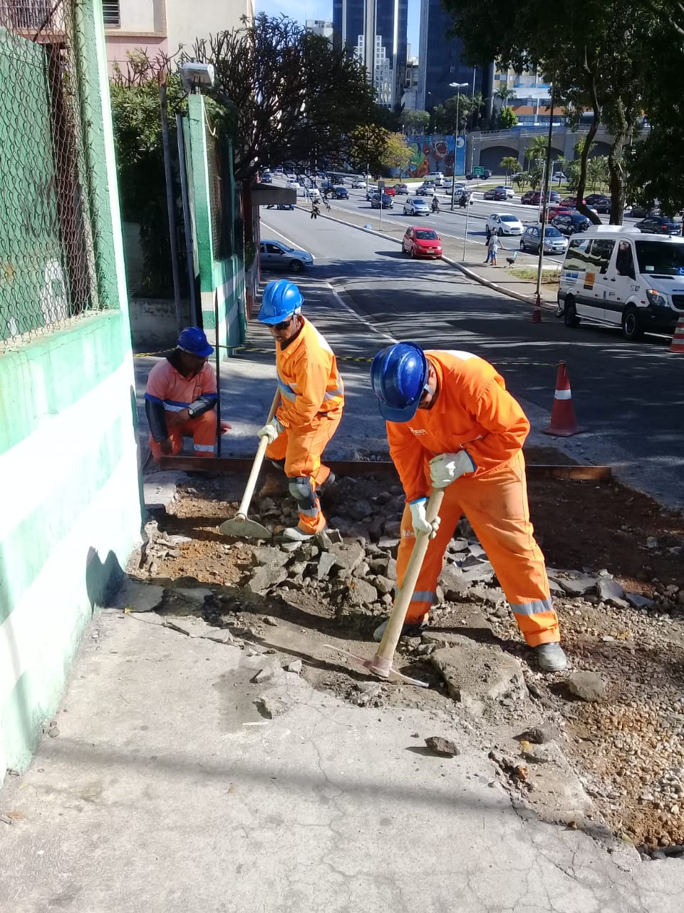 Três funcionários realizam reforma na calçada da Rua Jaceguaí. 