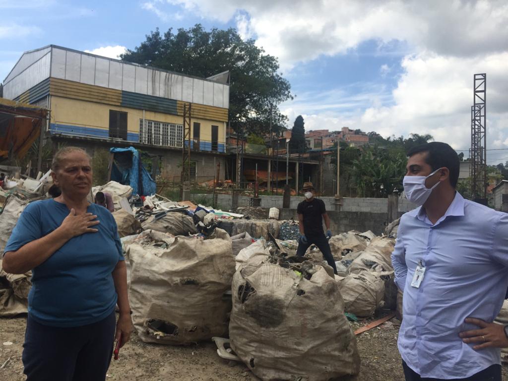 O subprefeito de São Mateus conversa com uma mulher, no meio de vários sacos do tipo bag cheios de materiais recicláveis.