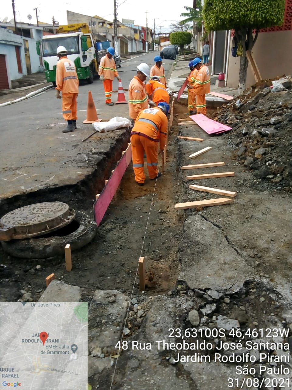 Equipe de oito homens com uniforme laranja trabalham na montagem das escoras de um canaletão que será reconstruído na rua Theobaldo José Santana, no Jardim Rodolfo Pirani. Um monte de entulho está ao lado. 