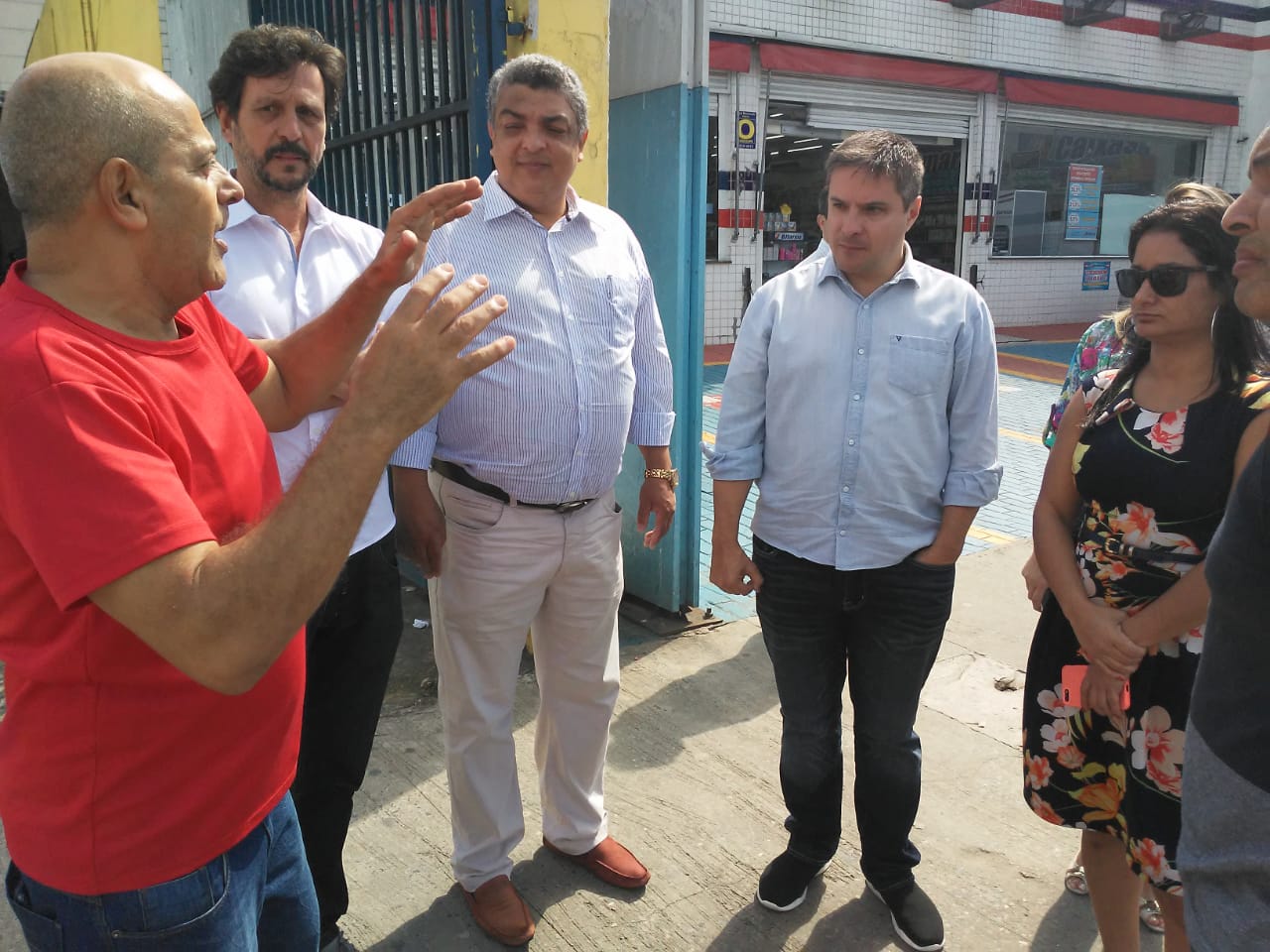 Foto mostra secretário Alexandre Modonezi, subprefeita Janaína Lopes, de Santo Amaro, e quatro pessoas em pé, em círculo, observando um presentes falar.