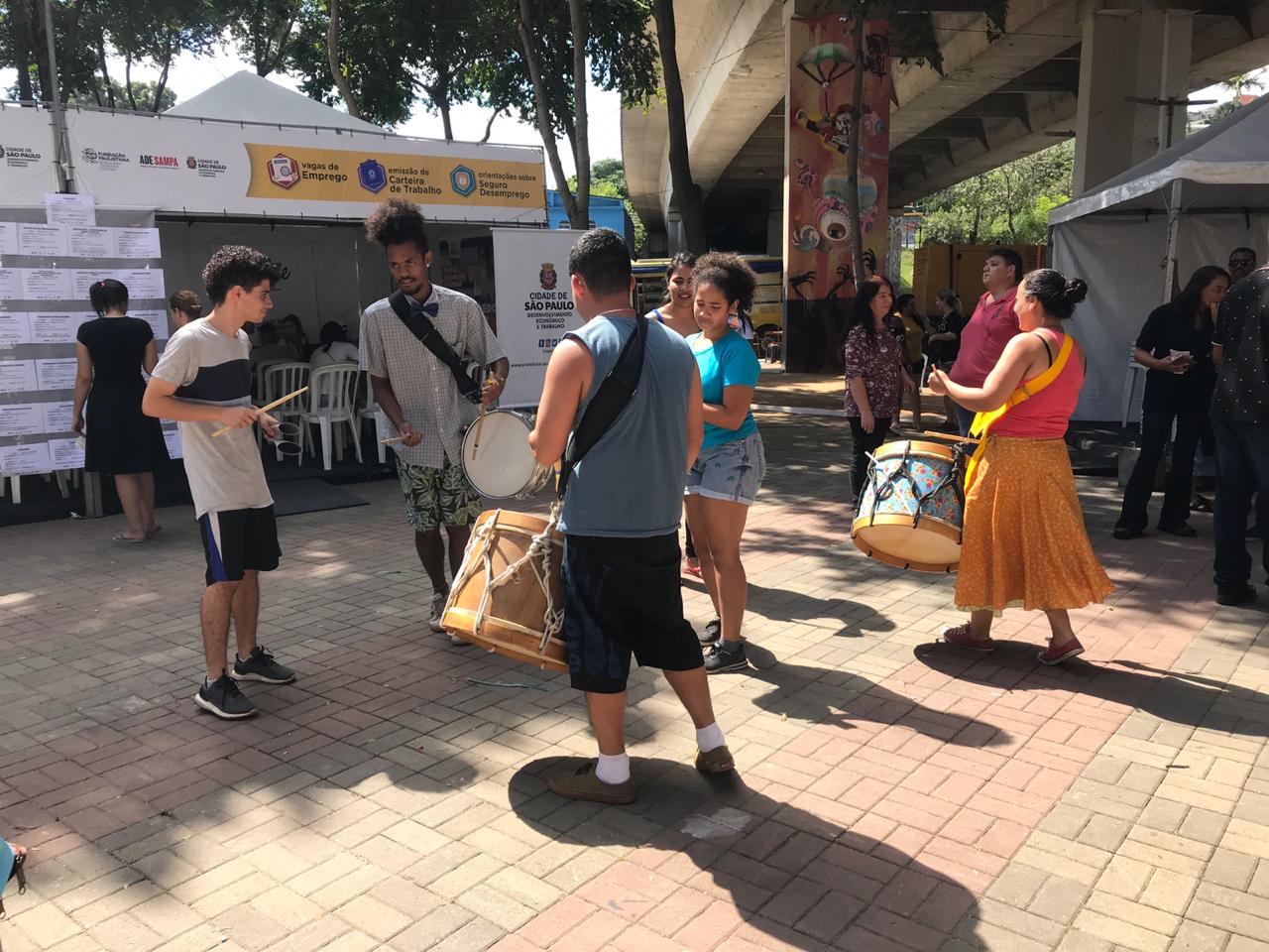 Cinco pessoas tocando instrumentos no meio da praça
