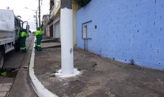 dois funcionários da Equipe de serviços está indo embora entrando no caminhão após a retirada da placa deixando o poste limpo e a calçada liberada