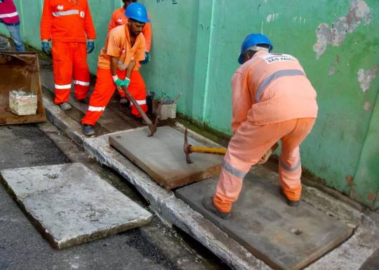 Equipe da Subprefeitura colocando uma nova tampa de bueiro