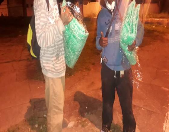 dois moradores de rua usando blusas de moletom recebem um cobertor para cada um em noite fria do bairro Tiradentes