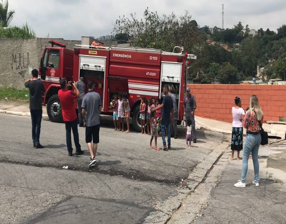 carro do corpo de bombeiros estacionado com crianças e moradores na participação do evento