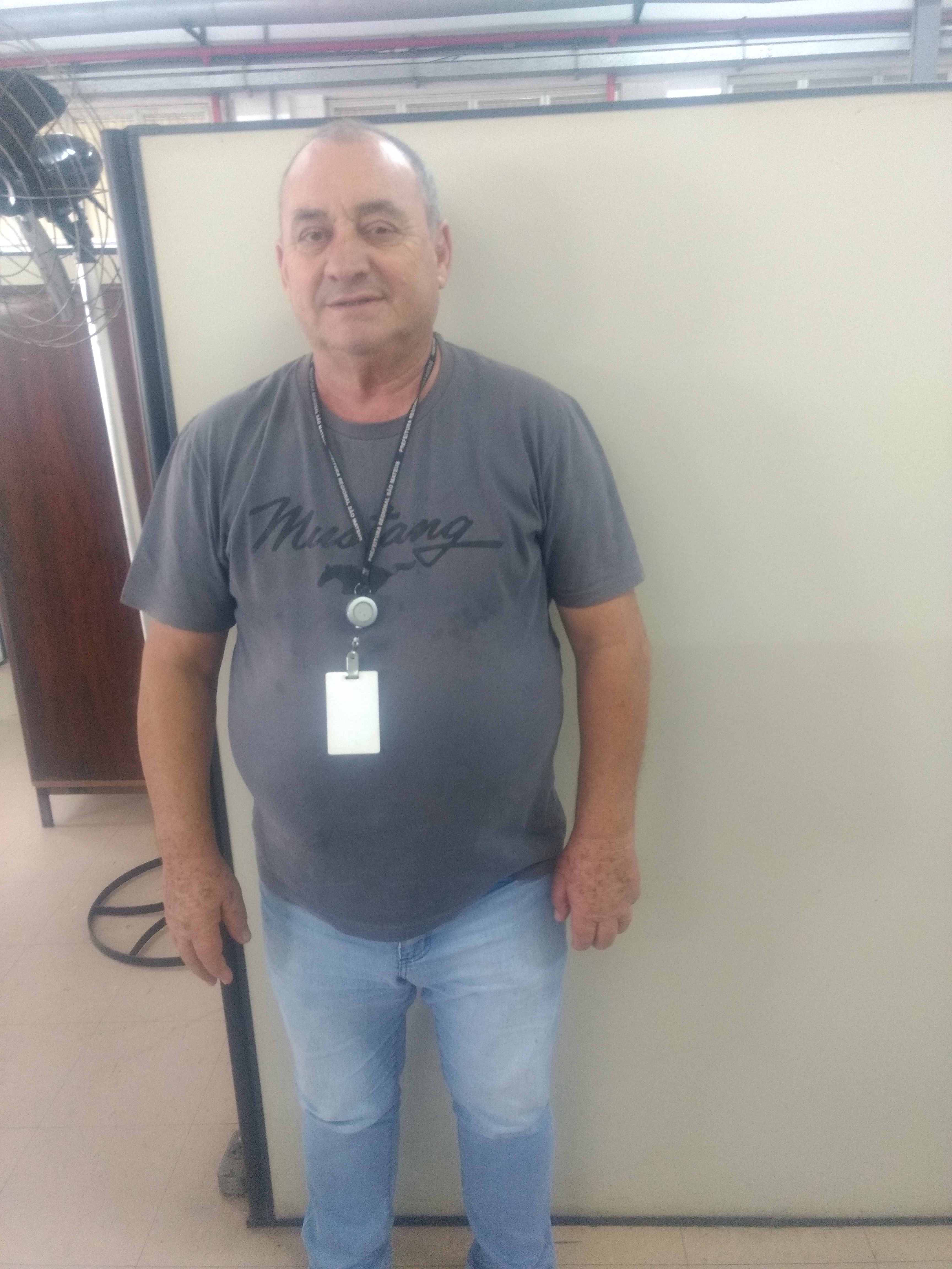 Michele em pé, vestindo camiseta cinza e calça jeans.