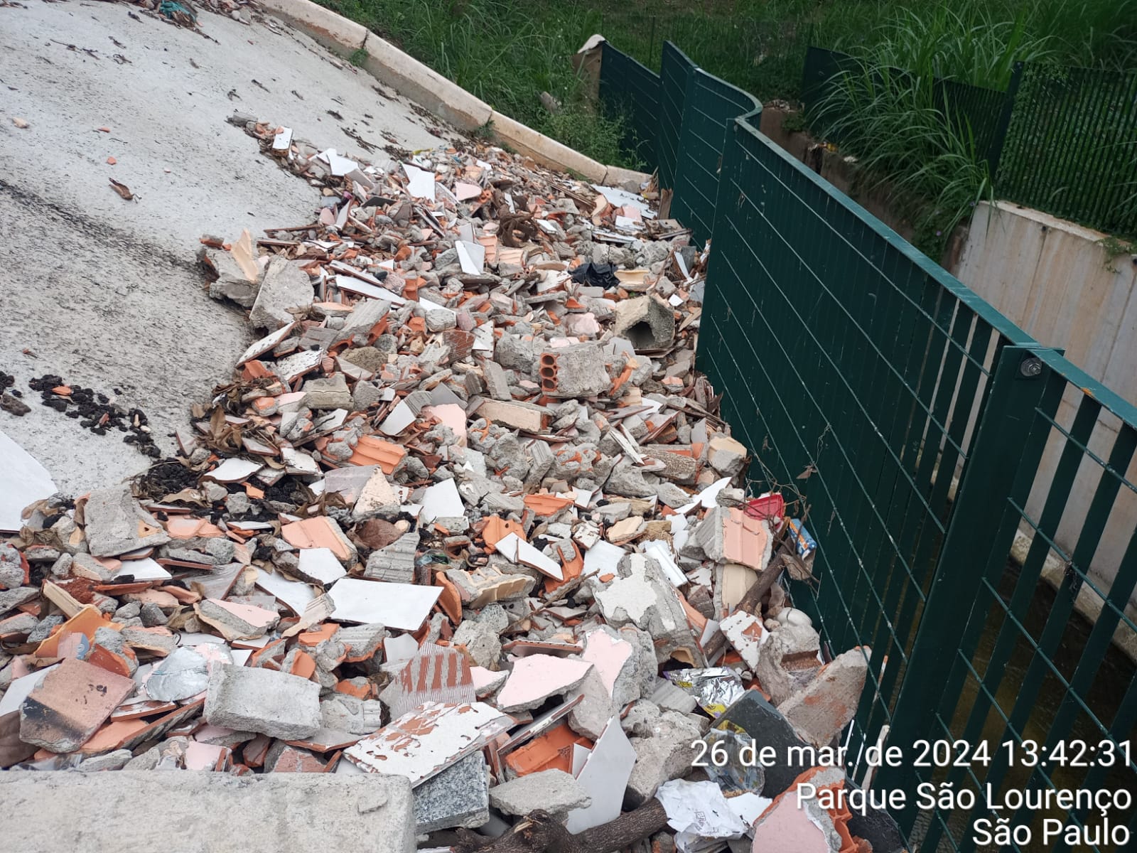 Entulho jogado em uma rampa à beira de um córrego. 