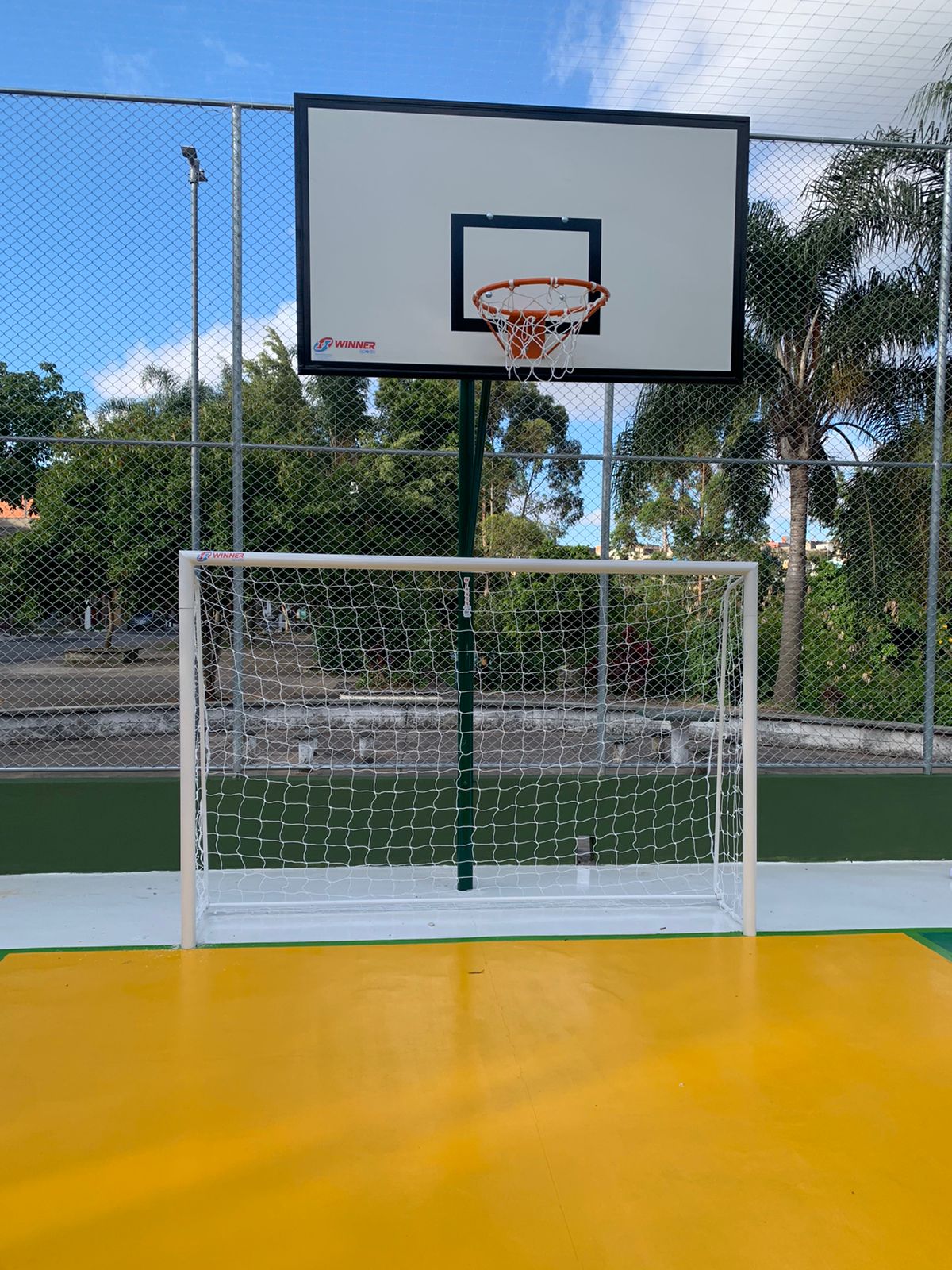 área do gol de uma quadra de esportes, pintada de amarelo e com a cesta de basquete acima da trave. 