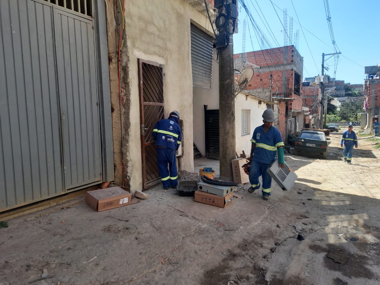 Funcionários da Sabesp realizam a instalação da rede dentro de uma casa.