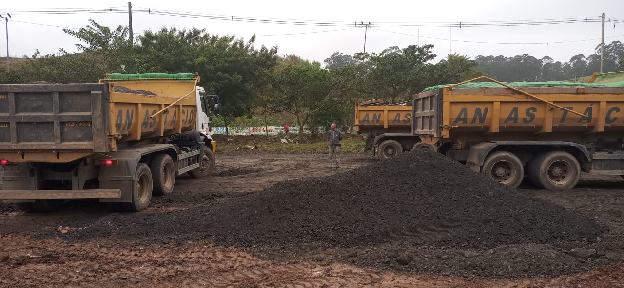 caminhão descarrega fresa de asfalto em terreno onde será construída a UBS. 