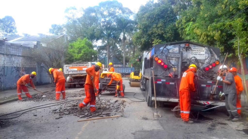 Profissionais da Operação Tapa Buraco trabalham em um rua da Vila Maria, três preparam o buraco, outros três pegam massa no caminhão de massaasfáltica