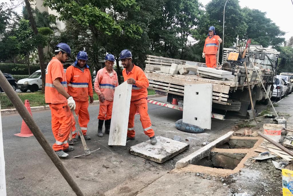 Imagem de funcionários efetuando a troca de duas tampas de bocas de lobo, na Av. José Maria Fernandes.