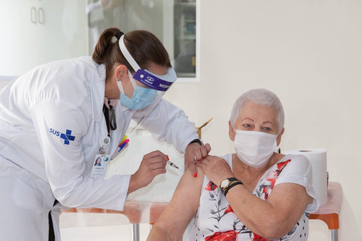 foto de idosa sendo vacinada no braço por uma enfermeira
