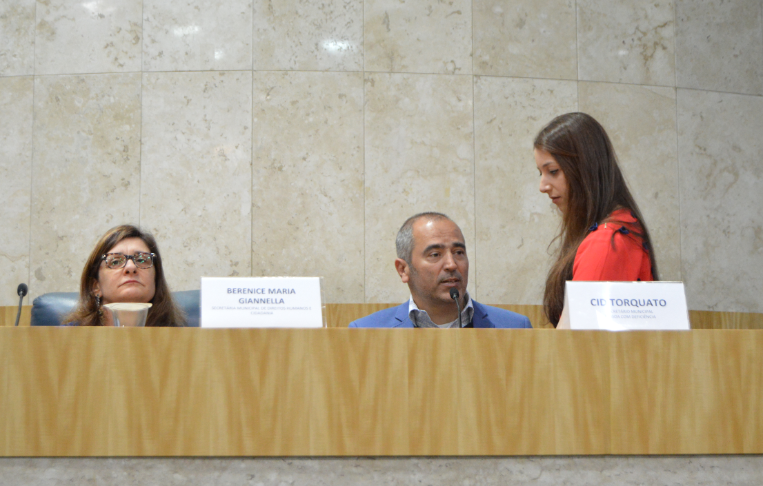 Secretário Municipal da Pessoa com Deficiência, Cid Torquato fala ao microfone, no palco,