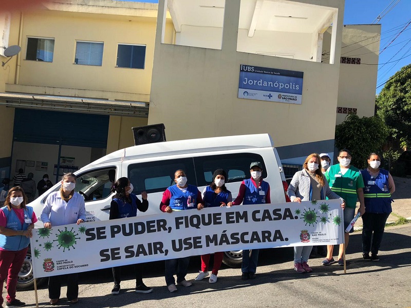 #PraCegoVer: Dez agentes de saúde enfileiradas. Elas estão segurando um banner que tem a frase "Se puder, fique em casa. Se sair, use máscara"