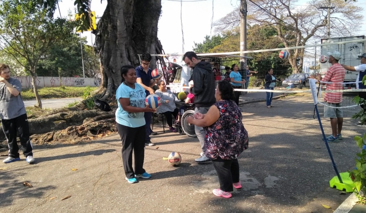 várias pessoas em uma praça jogam vôlei em uma rua.