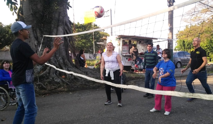 várias pessoas na foto jogam vôlei em uma rua.