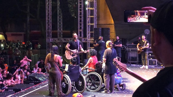 o cantor Lucas Lucco com mais de cinco pessoas com deficiência, no palco da Virada.