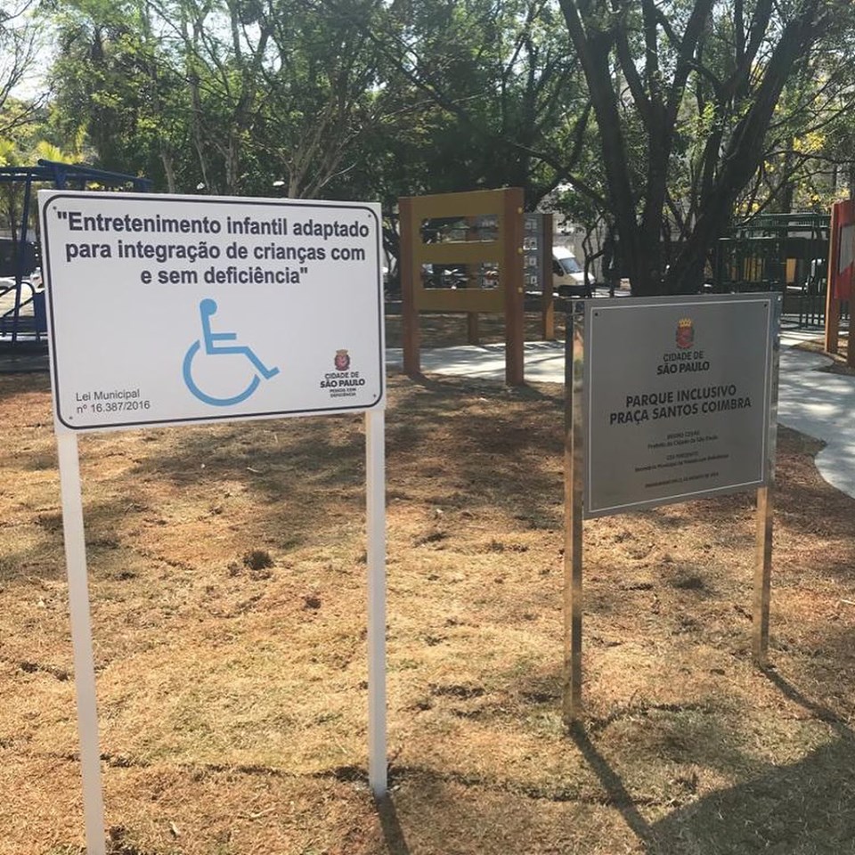 ao redor, árvores. Duas placas sinalizando acessibilidade e inauguração dos equipamentos. 