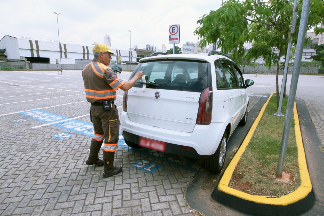 guarda da CET multando um carro estacionado em uma vaga reservada, 