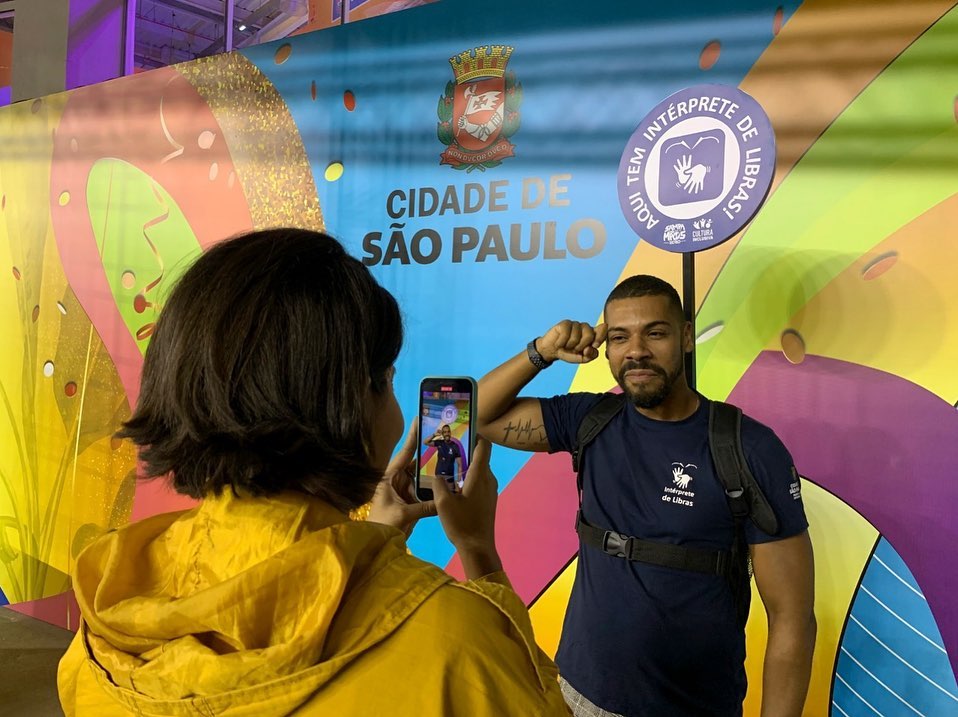 Duas pessoas. Uma das assessoras da SMPED realiza via redes sociais os stories em Libras. Intérprete na foto. 