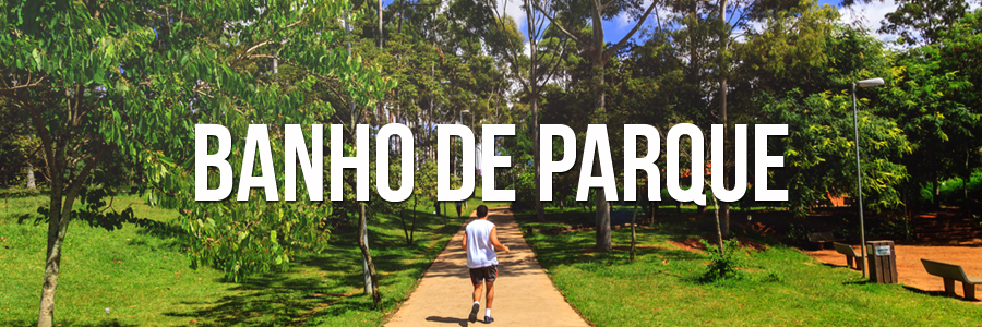 Foto de um homem com camiseta branca e bermuda preta, caminhando na pista, com grama e árvores verdes ao redor. Com a seguinte frase no meio em branco "Banho de parque"