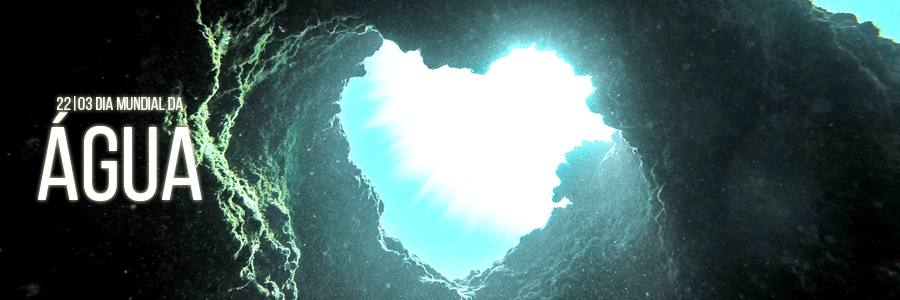 Fotografia do fundo do oceano, de dentro de uma espécie de gruta em que uma abertura em forma de coração dá vista para a água. À esquerda, está a frase: "22/03 - Dia Mundial da Água"