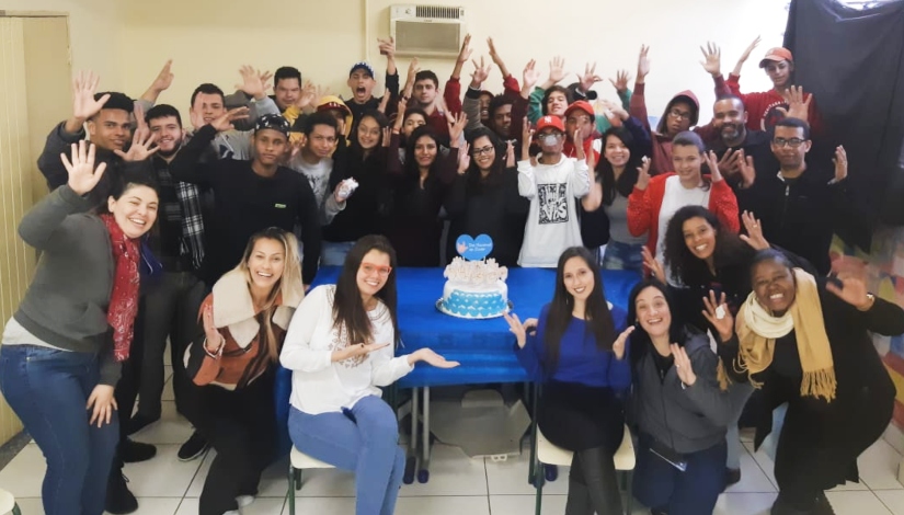 em uma sala de aula, mais de vinte pessoas na foto, alunos e professores.