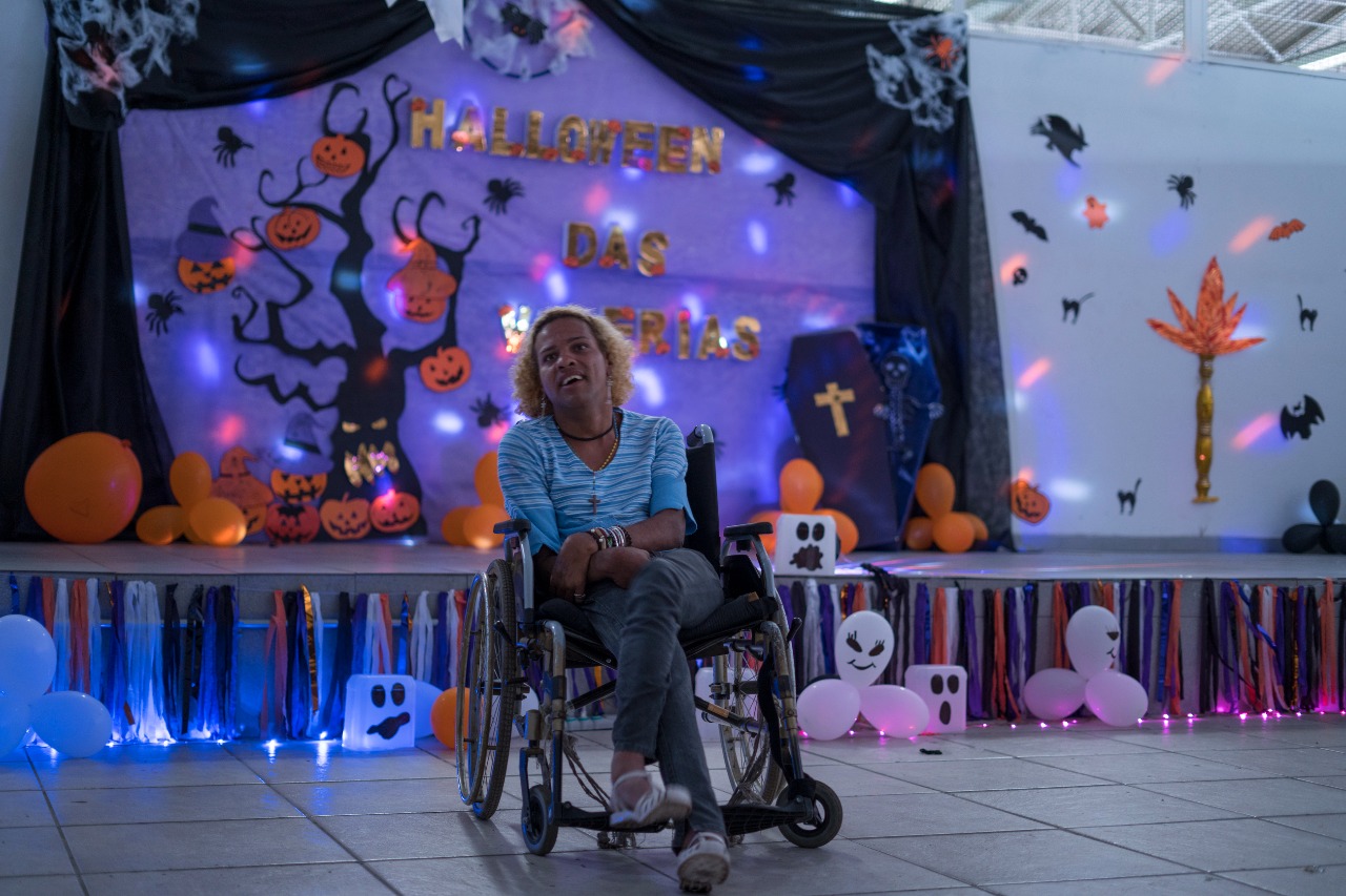 Em um fundo de decoração de halloween, uma convivente cadeirante sorri