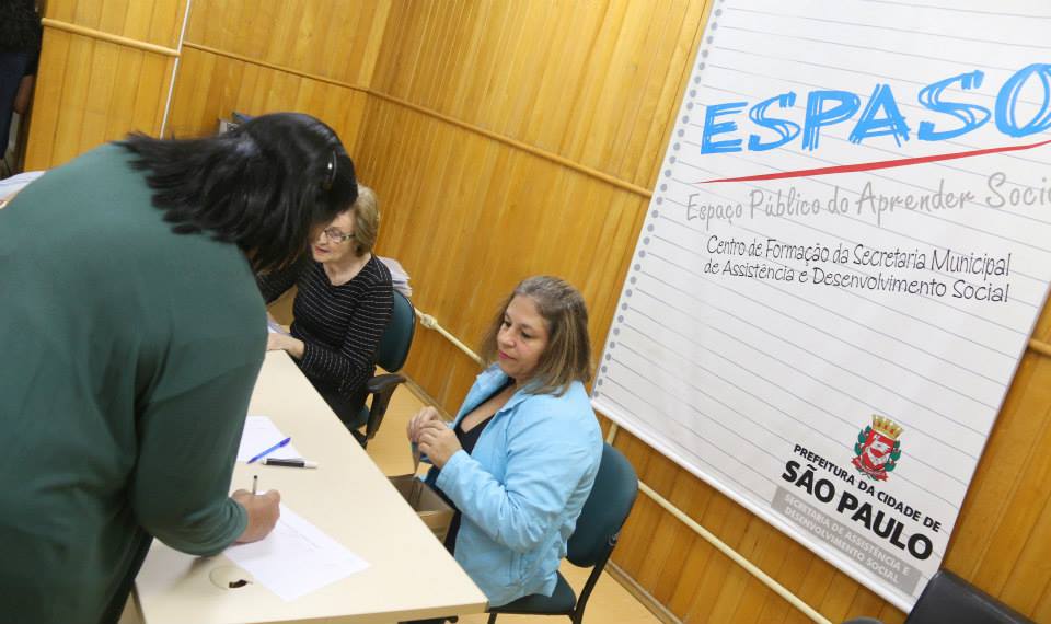 Na foto, uma pessoa está assinando um documento enquanto é atendida no ESPASO