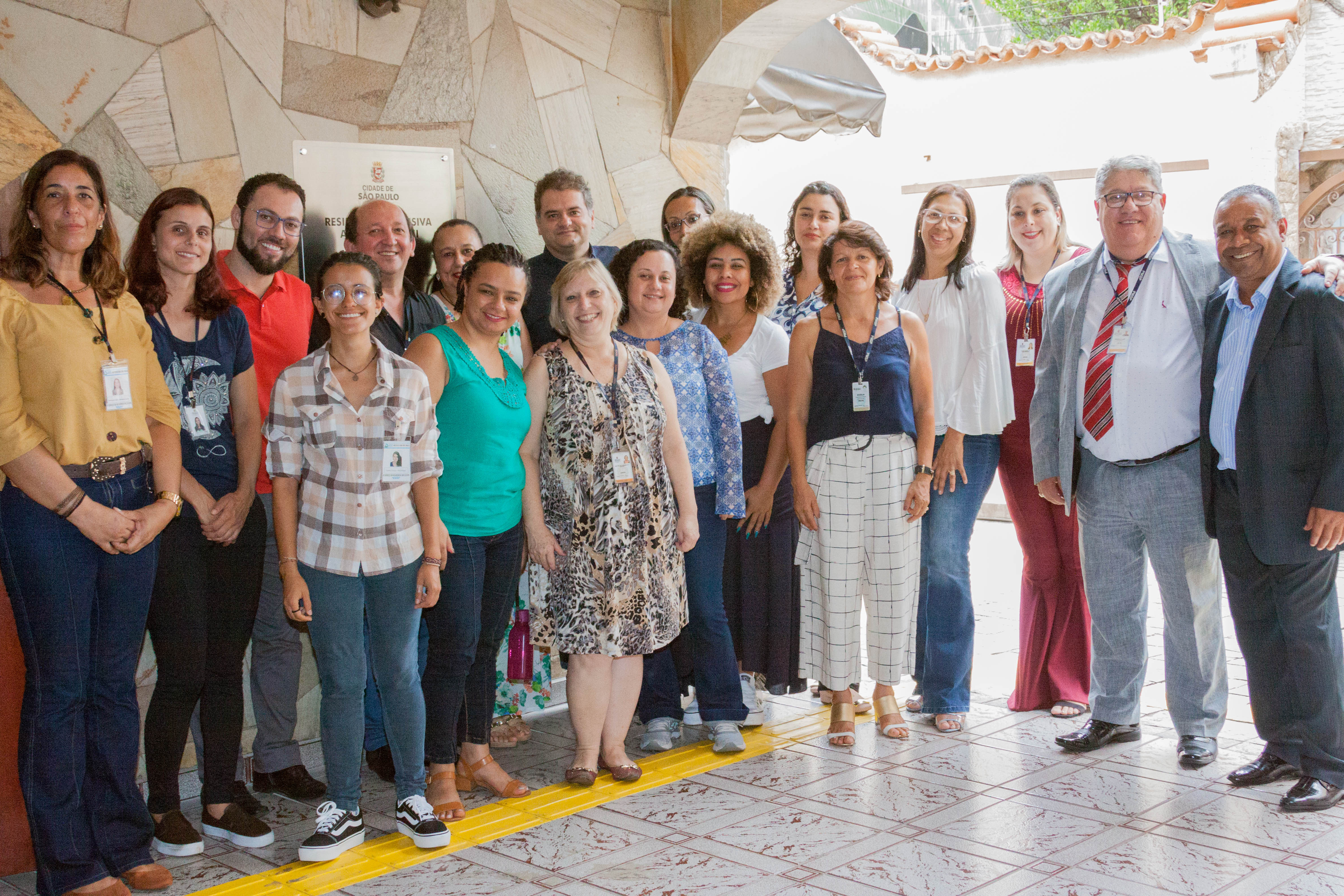 Dezoito pessoas posam para foto, dentre eles o secretário-adjunto da Secretaria Municipal de Assistência e Desenvolvimento Social; a Supervisora de Assistência Social da Penha, Marcia Selles; a presidente do Instituto Vida São Paulo, Andreia Neves dentre outras autoridades.