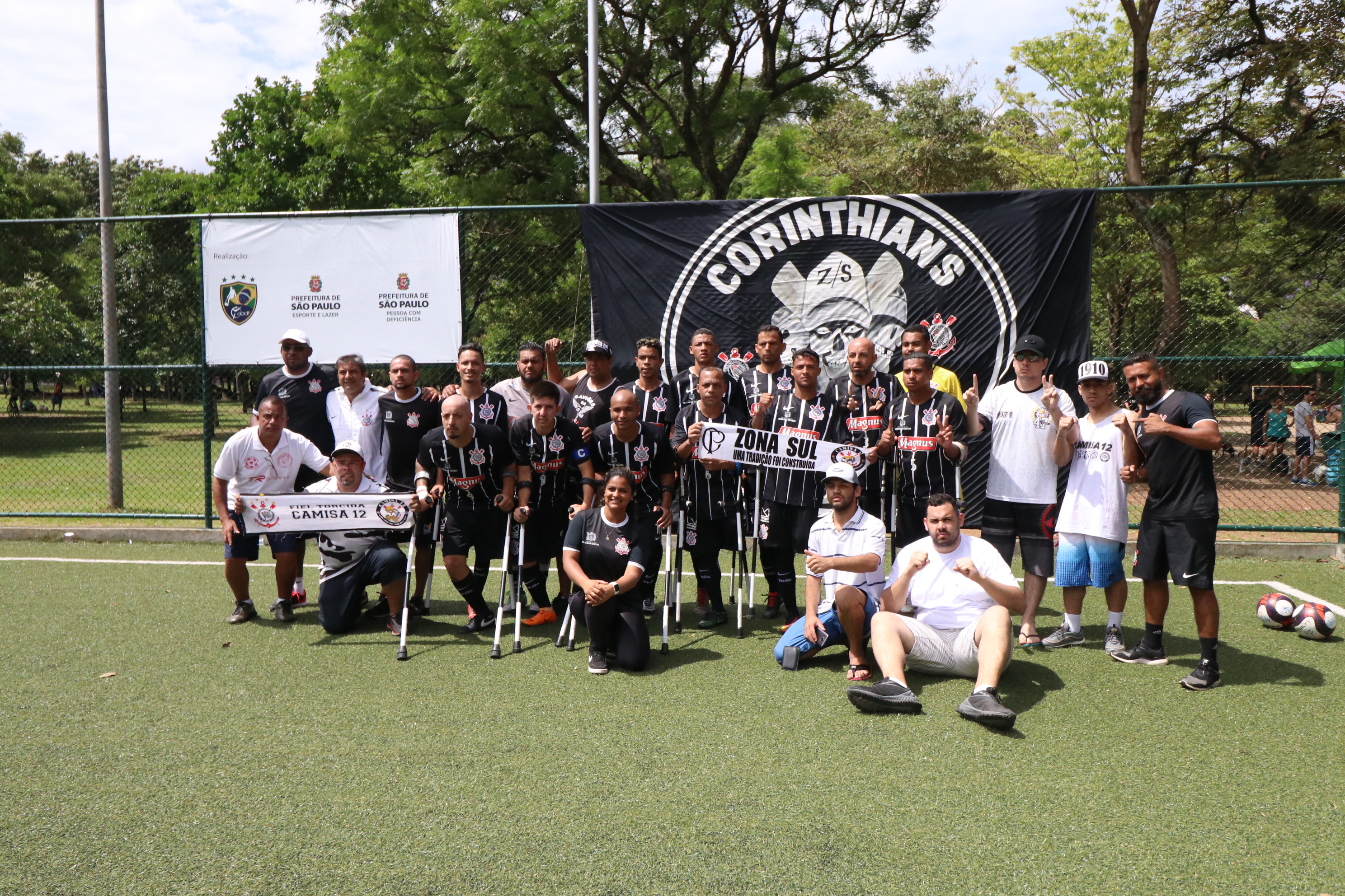 Time do Corinthians e equipe técnica reunidas no campo de futebol com a faixa de campeão. 