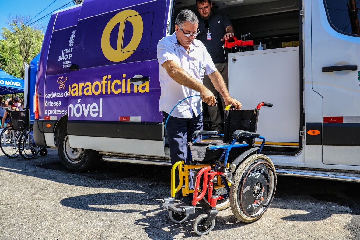 paraoficina estacionada e técnico arruma cadeira de rodas.
