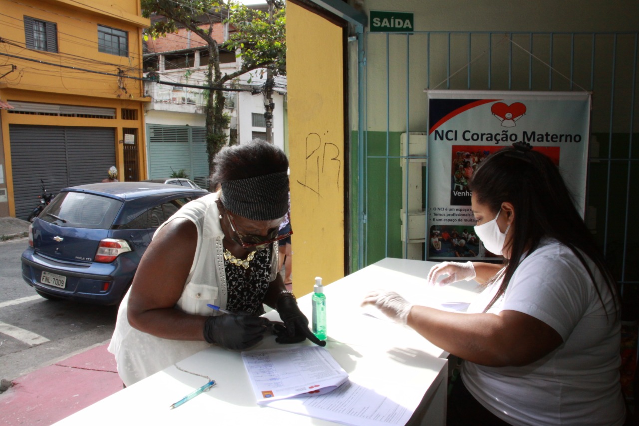 Usuária do Núcleo de Convivência de Idosos Coração Materno assina documento que autoriza a retirada da cesta básica.