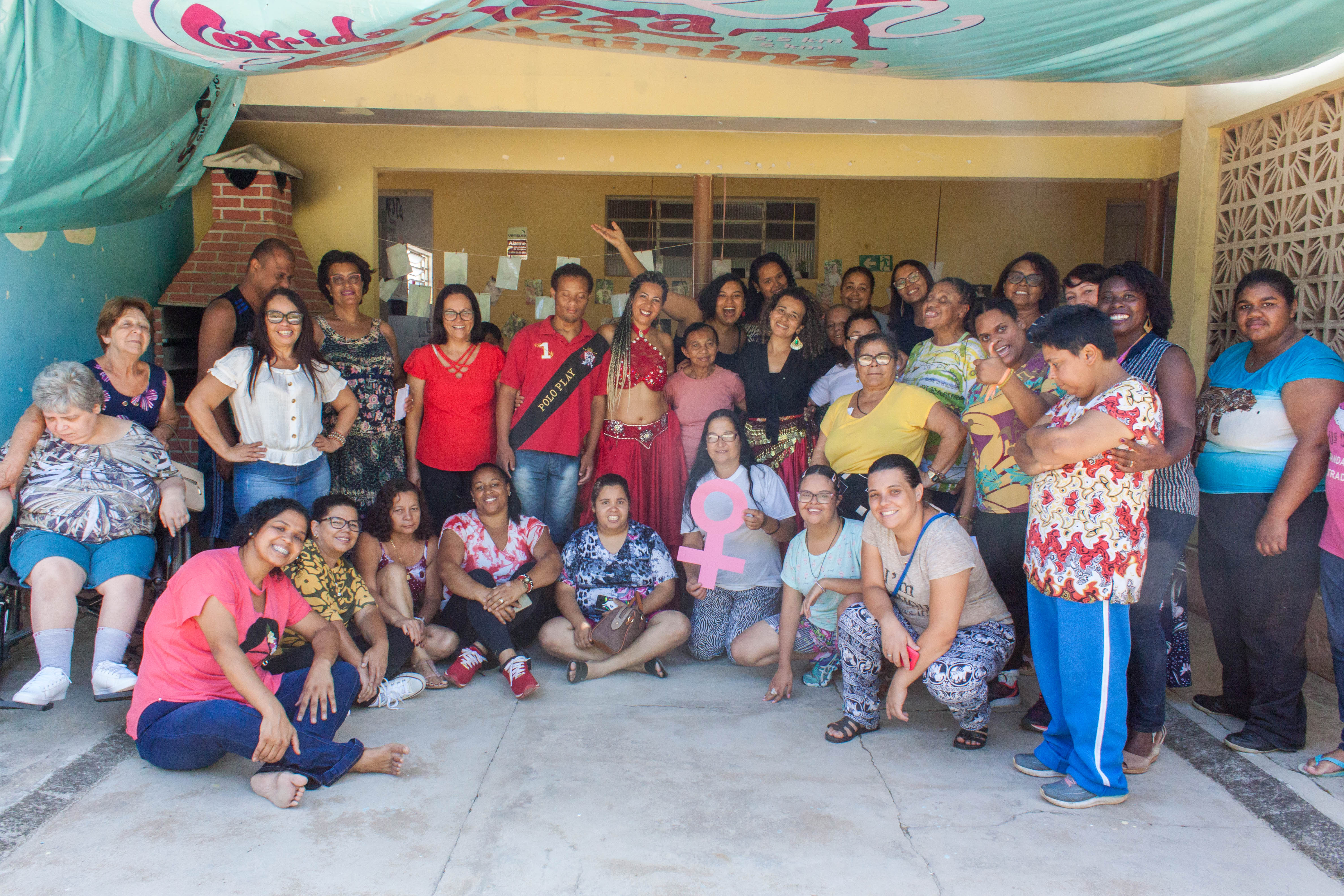 Várias pessoas posam sorrindo para a foto em área interna. 