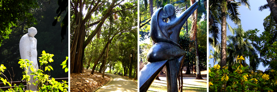 Um retângulo com quatro fotografias dentro, separadas por uma fina linha branca. A primeira foto uma escultura de uma mulher segurando um bebê, a segunda foto uma trilha com folhas secas na lateral, a terceira foto escultura de um casal dançando tango, a quarta foto arbustos com flores amarelas e árvores ao fundo.