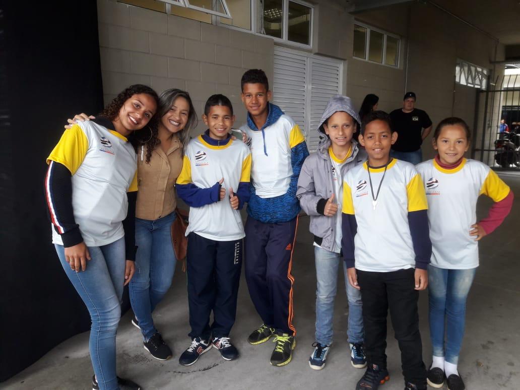 Crianças e instrutores juntos em pé no kartódromo 