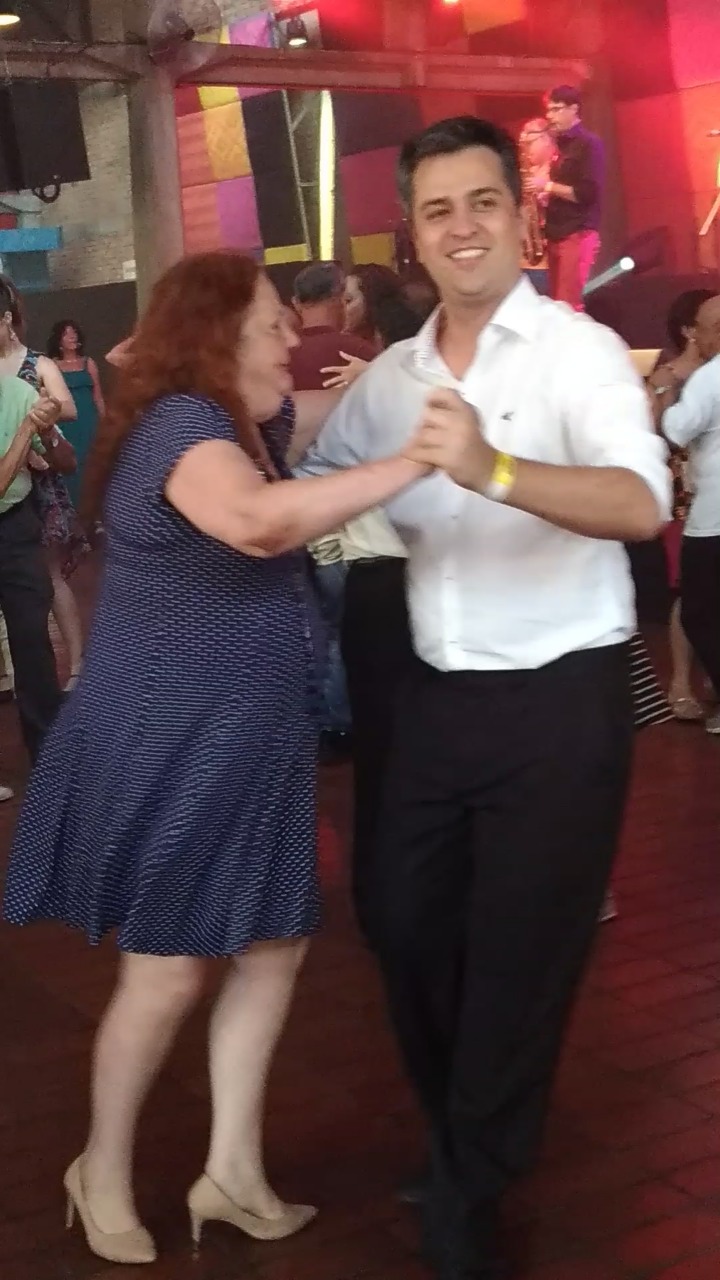 Idosa na pista de dança com dançarino no Sesc Pompéia