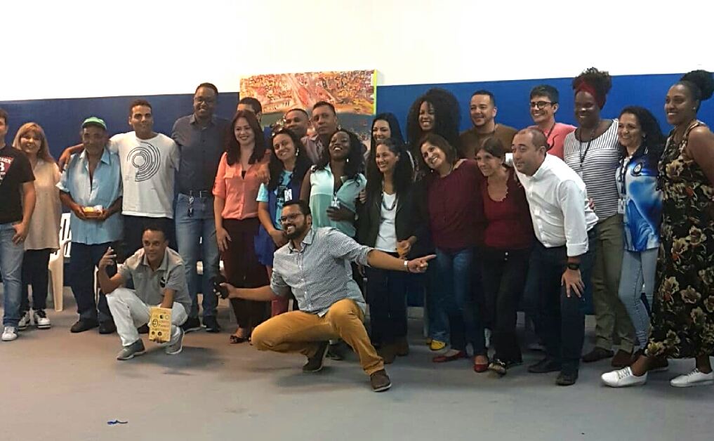 Vinte e duas pessoas, entre homens e mulheres, em pé e dois homens agachados na frente em pose para foto