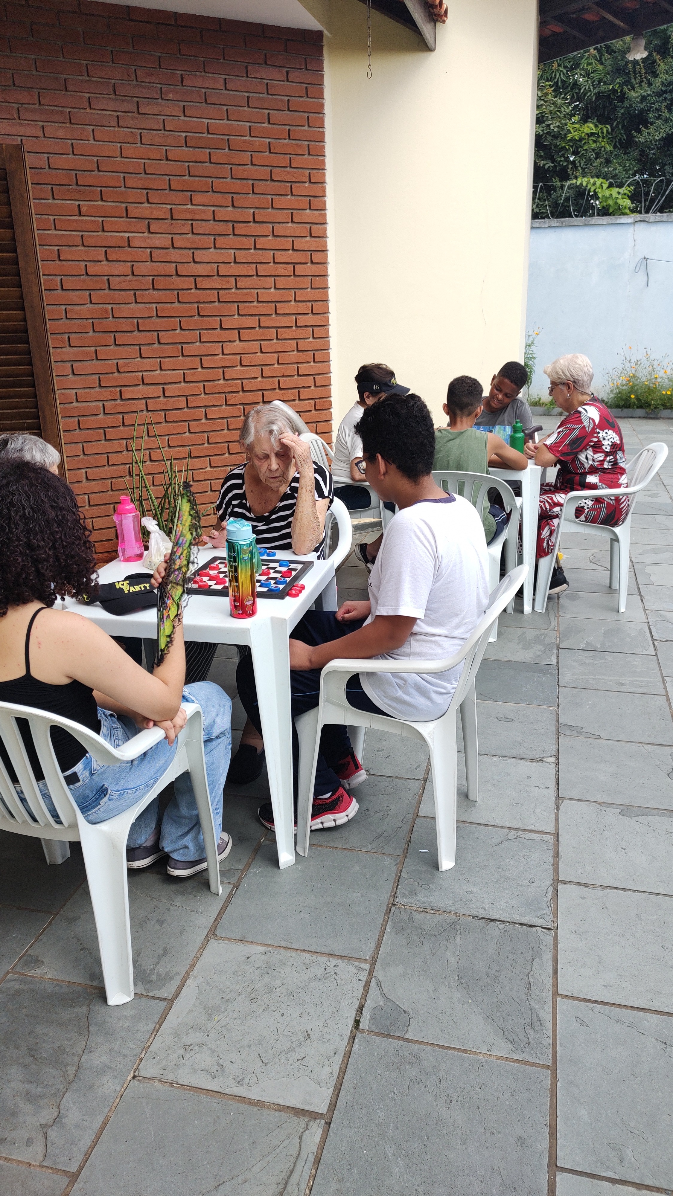 Jovens e idosos jogam damas em mesa no CDI Penha