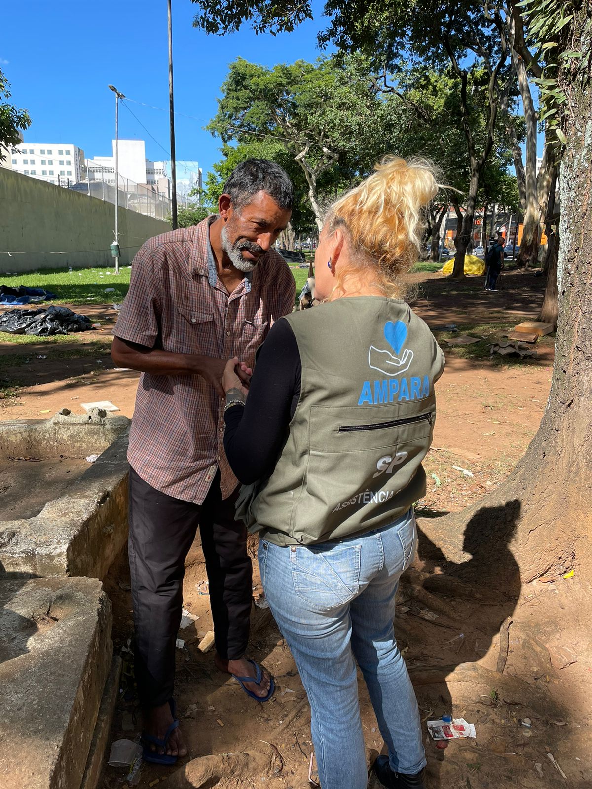 Mãos dadas entre a pessoa em situação de rua e o profissional do Ampara SP no atendimento social.